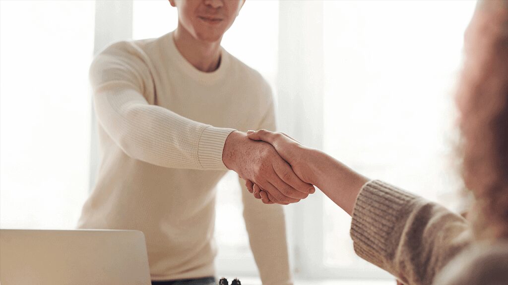 Two people shaking hands in a room.